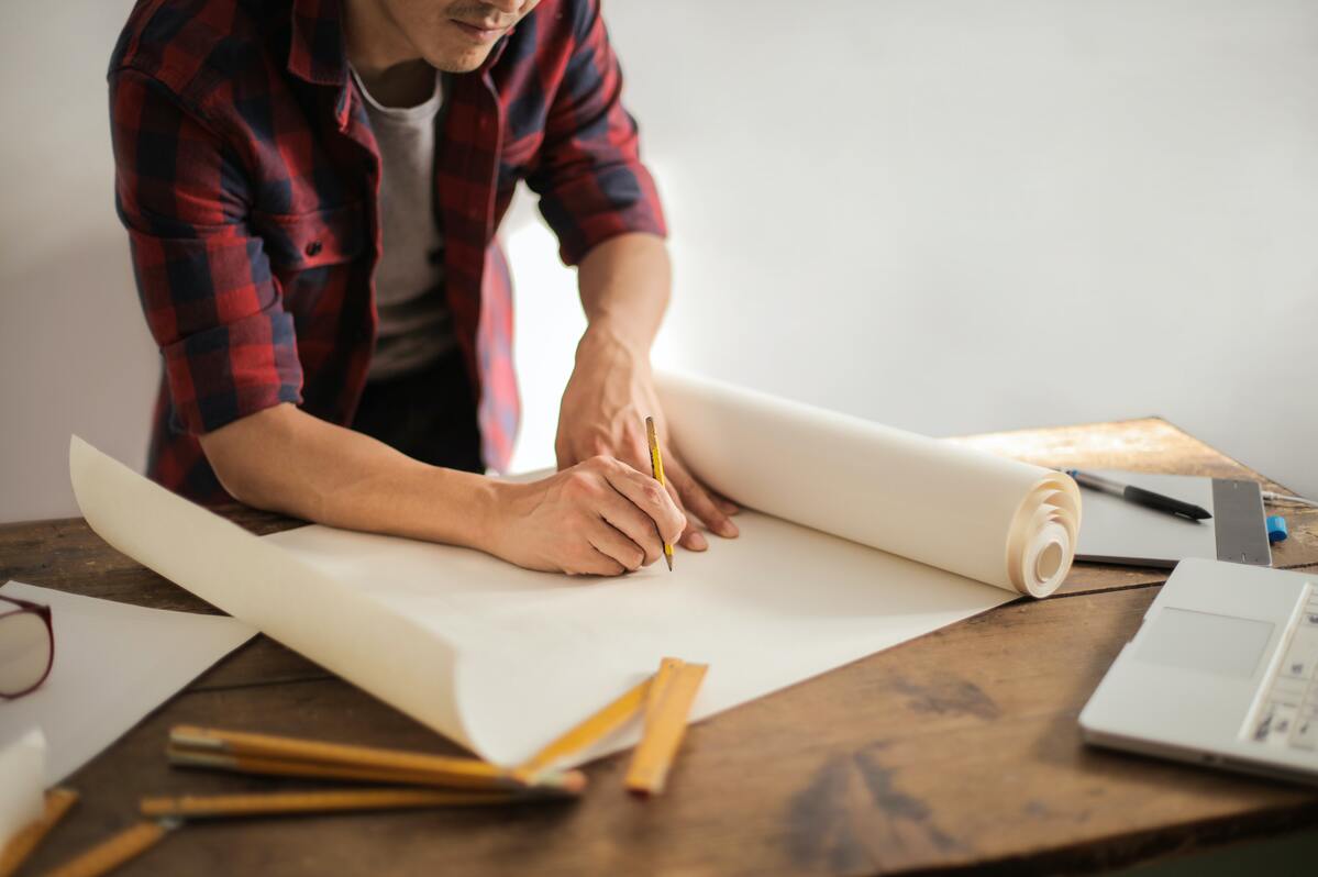 Seorang kontraktor sedang mengambar pada kertas.